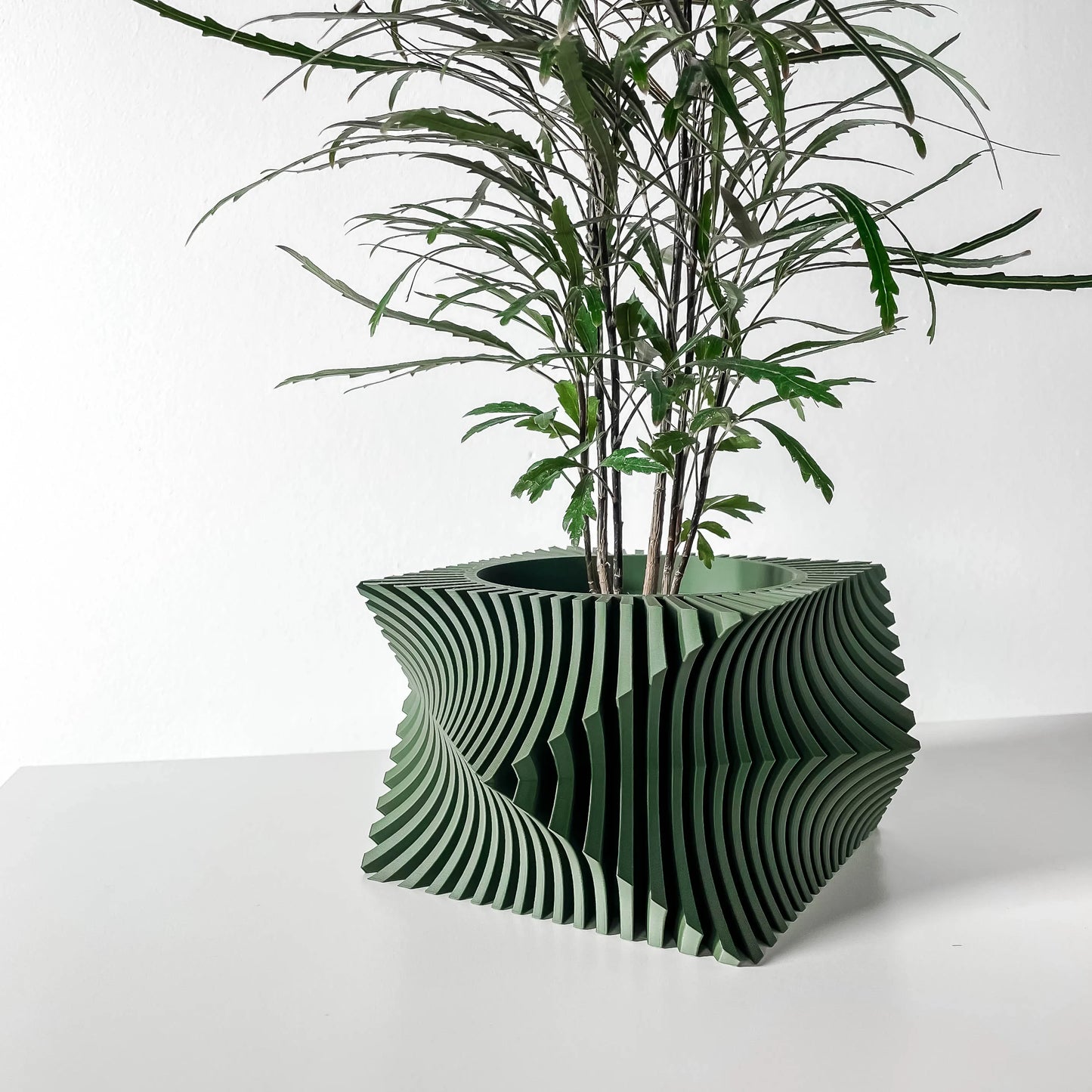 Pot décoratif anthracite en matériau durable au design contemporain ondulé avec une plante verte élégante.