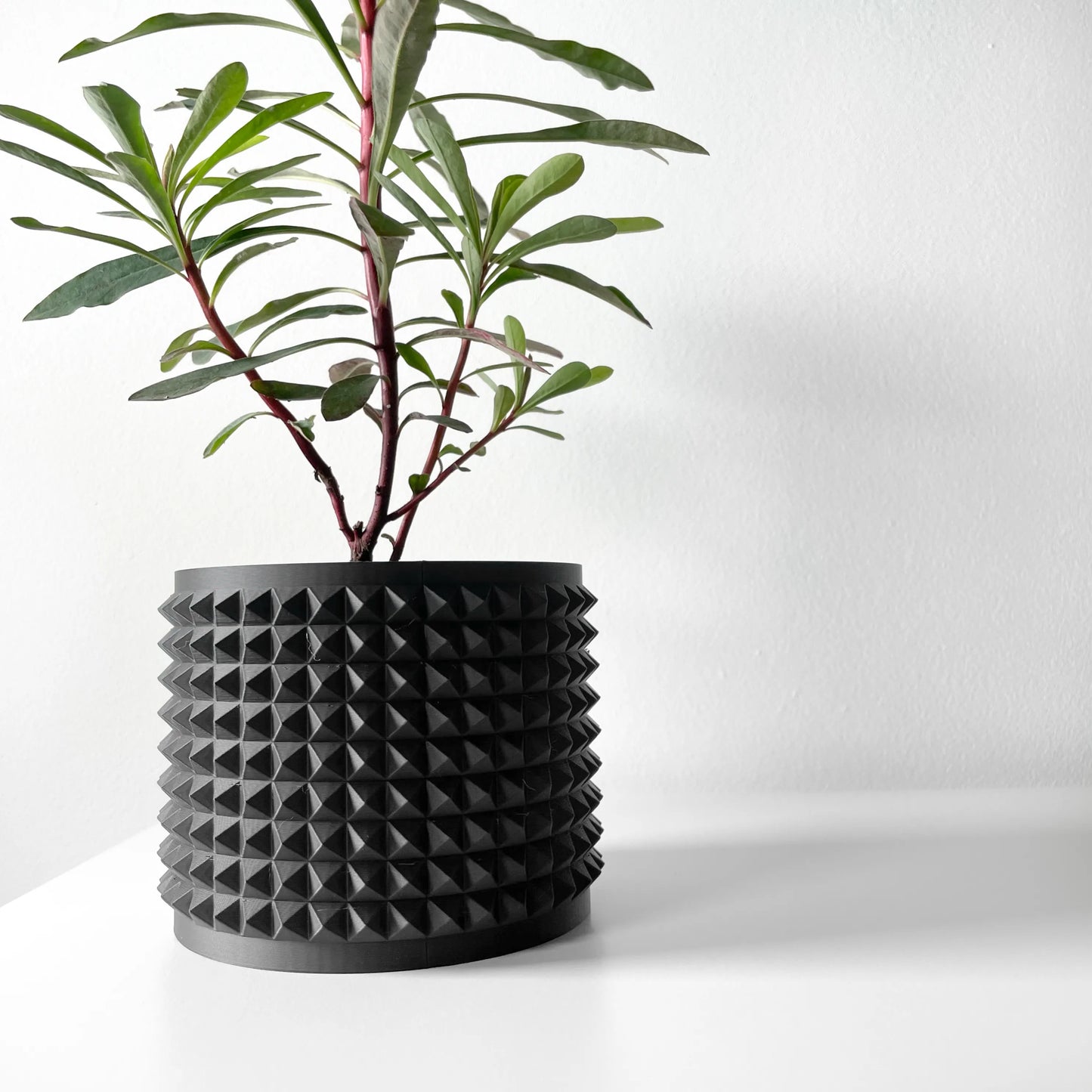 Pot décoratif anthracite en matériau durable avec design contemporain à surface texturée en pyramides régulières.