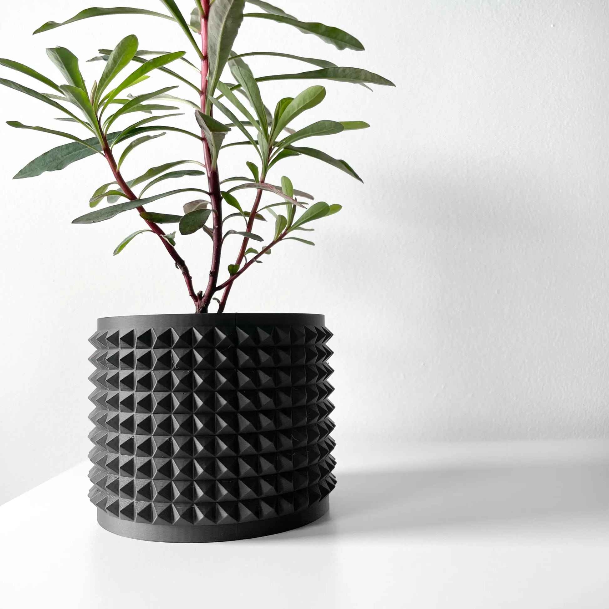 Pot décoratif anthracite en matériau durable avec design contemporain à surface texturée en pyramides régulières.