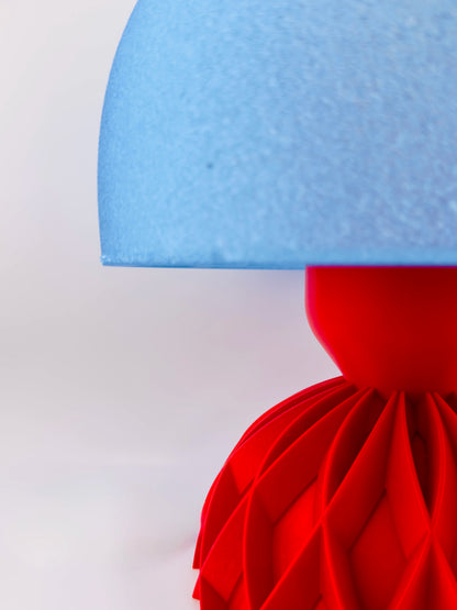 Lampe Arkan design contemporain avec abat-jour translucide bleu texturé et base rouge sculpturale en plastique durable.