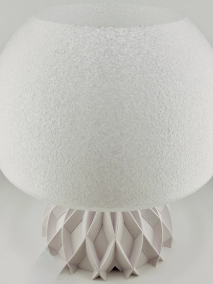 Lampe de table design contemporain avec abat-jour texturé blanc opaque et base sculpturale en plastique durable gris clair.