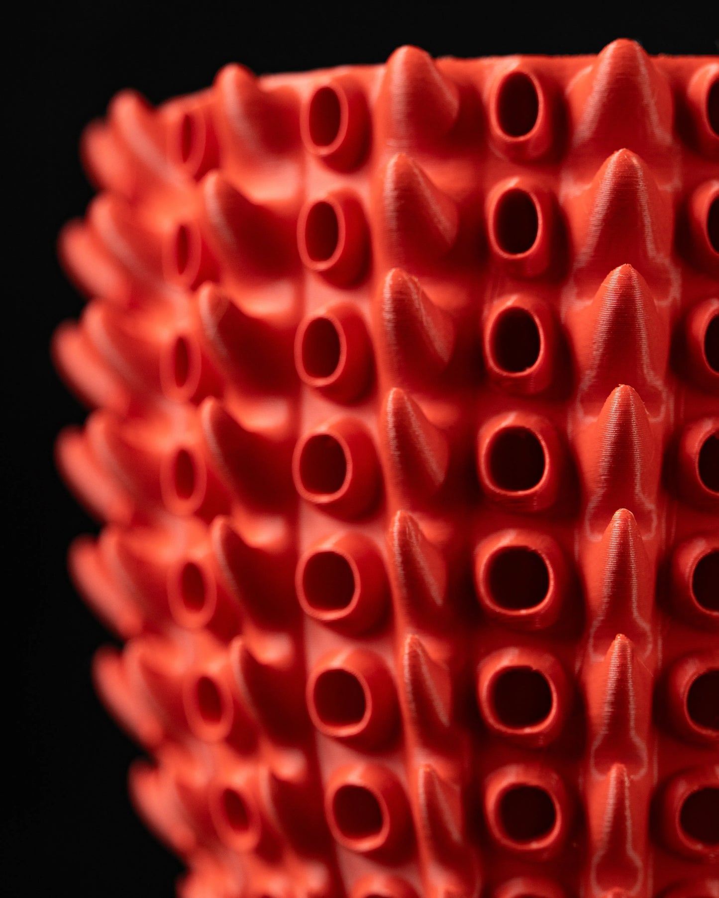 Pot décoratif rouge vif avec texture tubulaire en relief rappelant des branches de corail, surface mate et structure moderne.