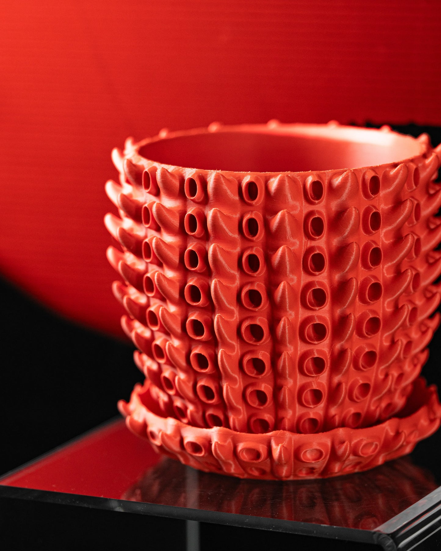 Pot décoratif orange en matériau durable avec design contemporain et reliefs en forme de petites excroissances organiques.