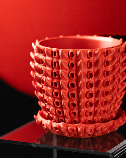 Pot décoratif orange en matériau durable avec design contemporain et reliefs en forme de petites excroissances organiques.