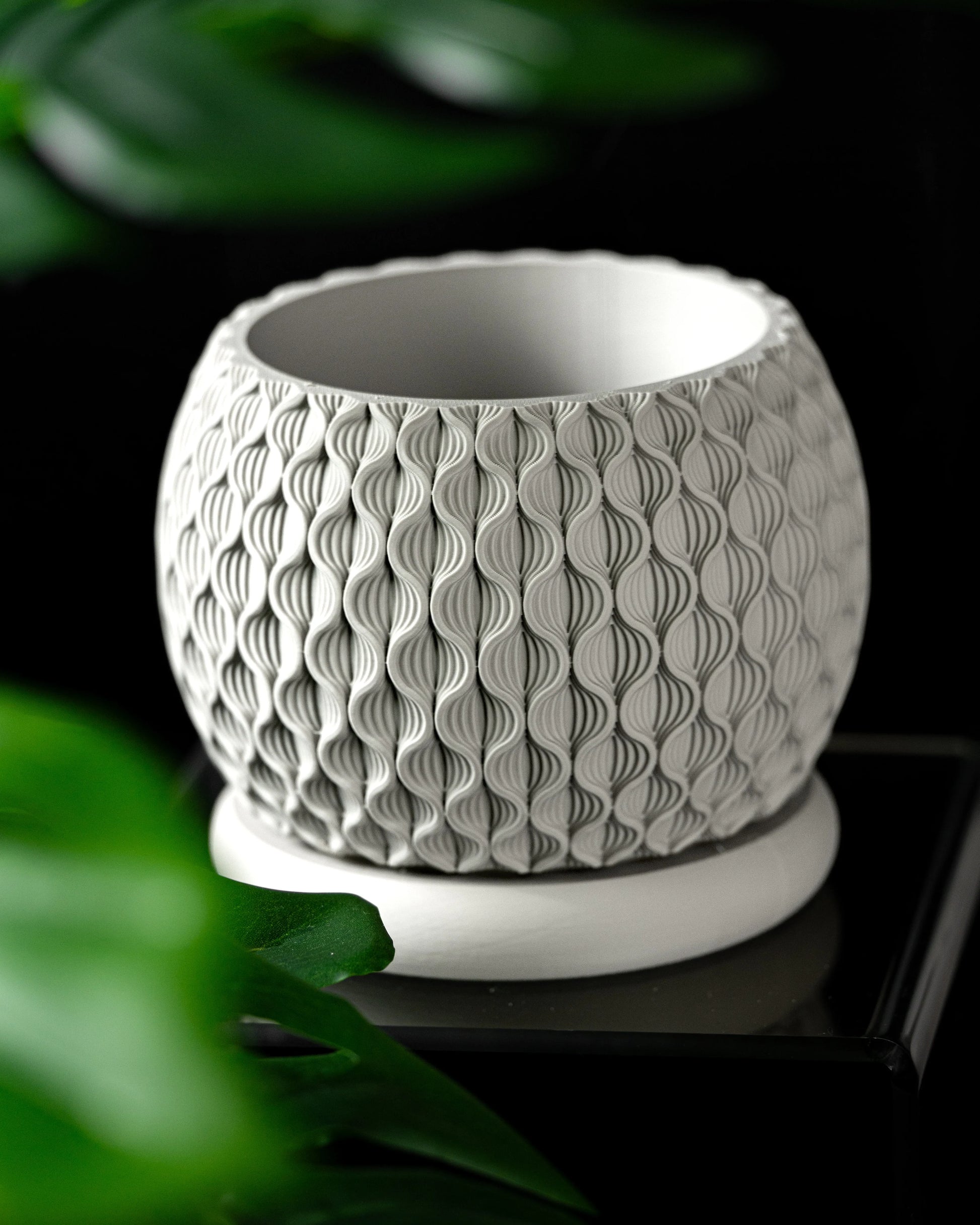 Pot décoratif rond blanc avec surface texturée en motifs géométriques en relief, posé sur un socle circulaire assorti.