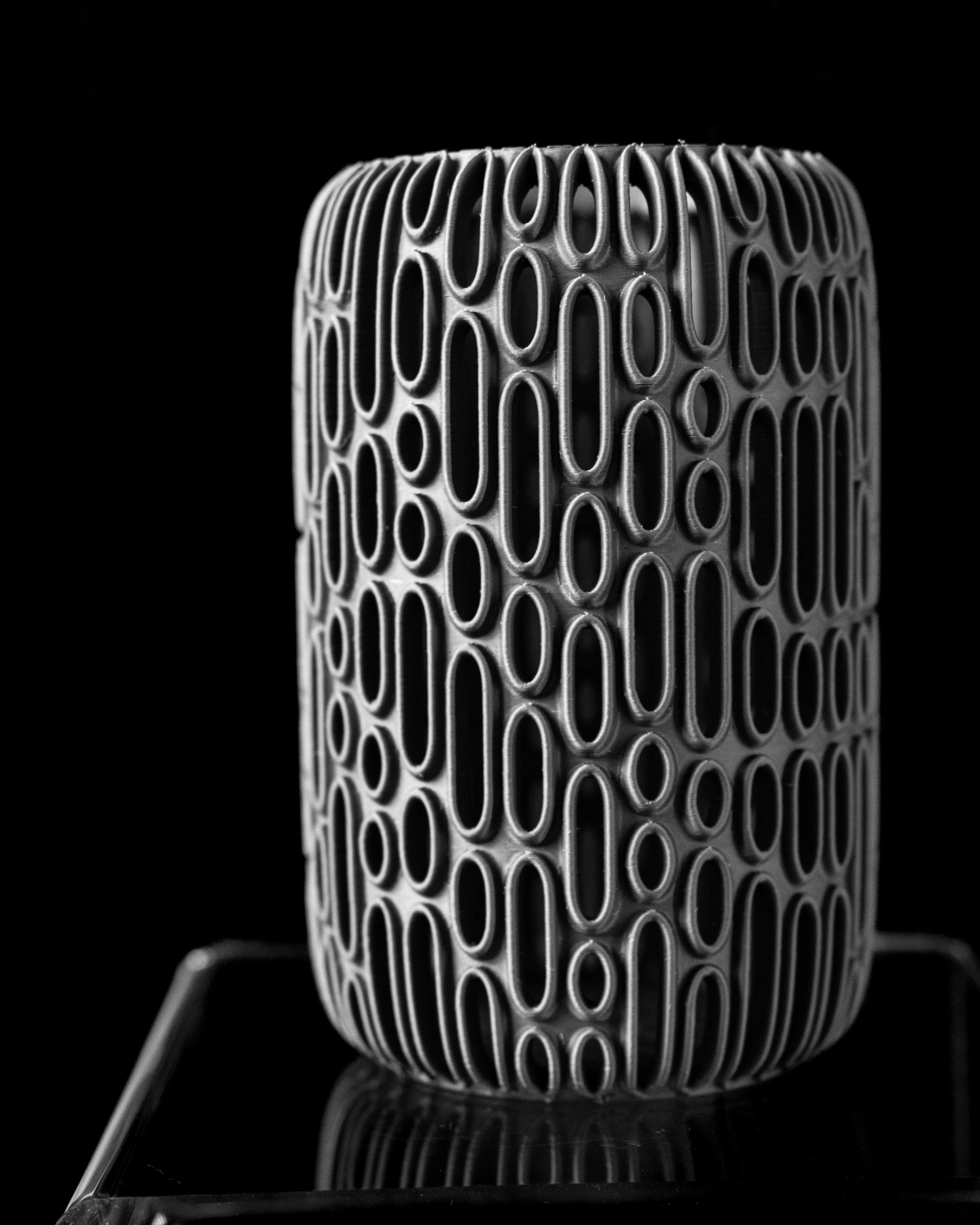 Vase cylindrique gris foncé avec motifs ovales en relief rappelant des bulles allongées sur toute la surface, aspect mat et.