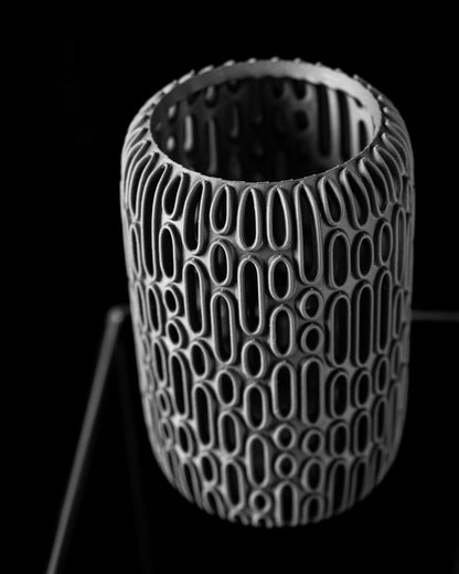 Vase cylindrique blanc à motifs ovales en relief, style moderne et minimaliste, surface texturée.