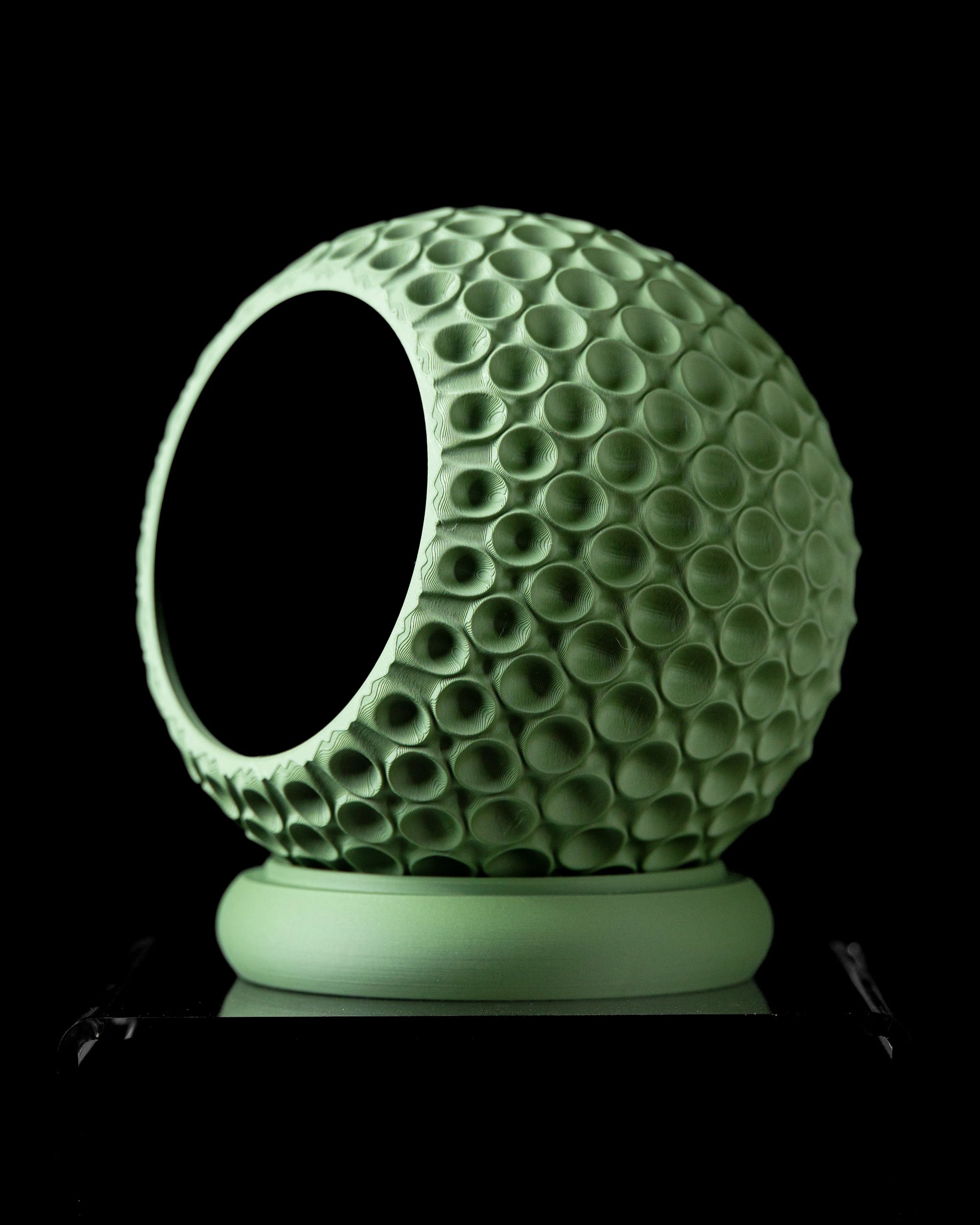 Pot décoratif vert menthe en forme de sphère avec texture de bulles circulaires, base ronde plate, intérieur creux noir.