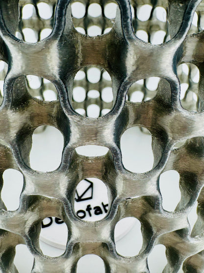 Suspension en polycarbonate noir translucide ajourée avec motif maillage graphique, design contemporain et durable.