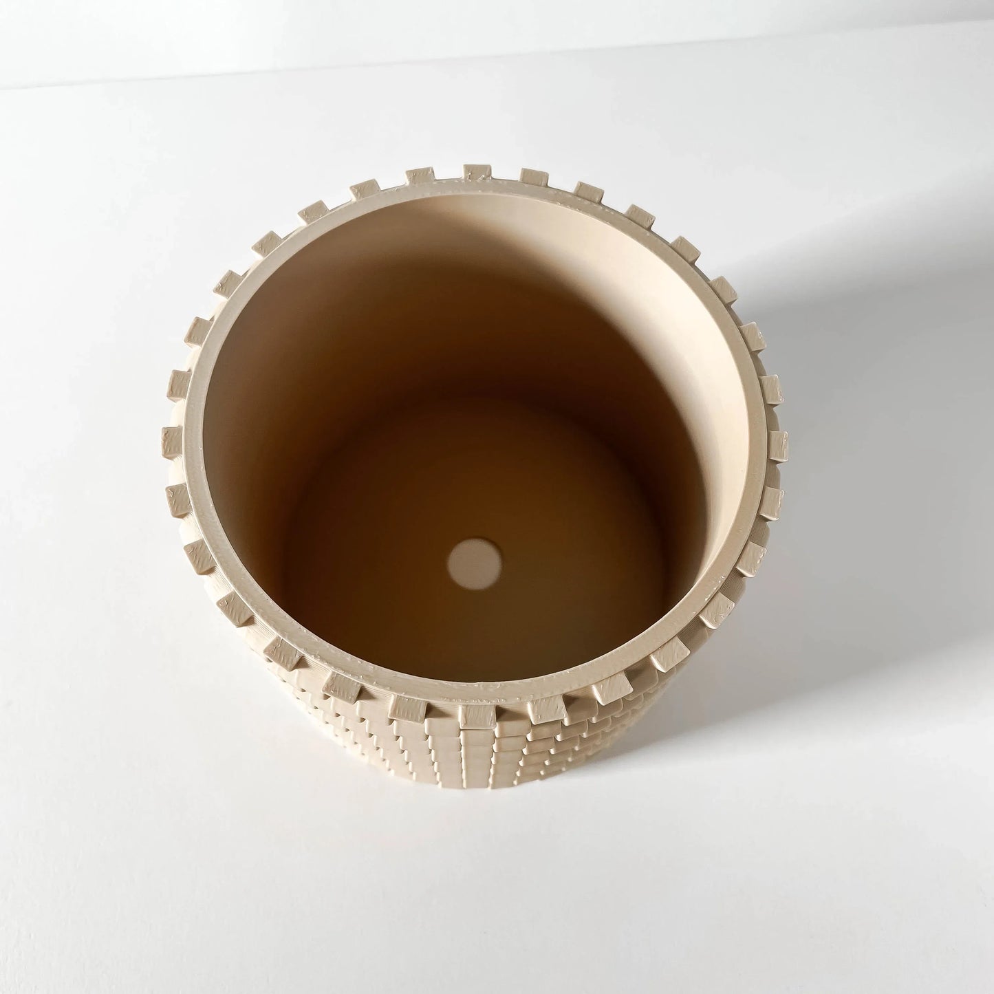 Pot décoratif rond beige avec bordure crantée et surface texturée en relief, style moderne industriel.