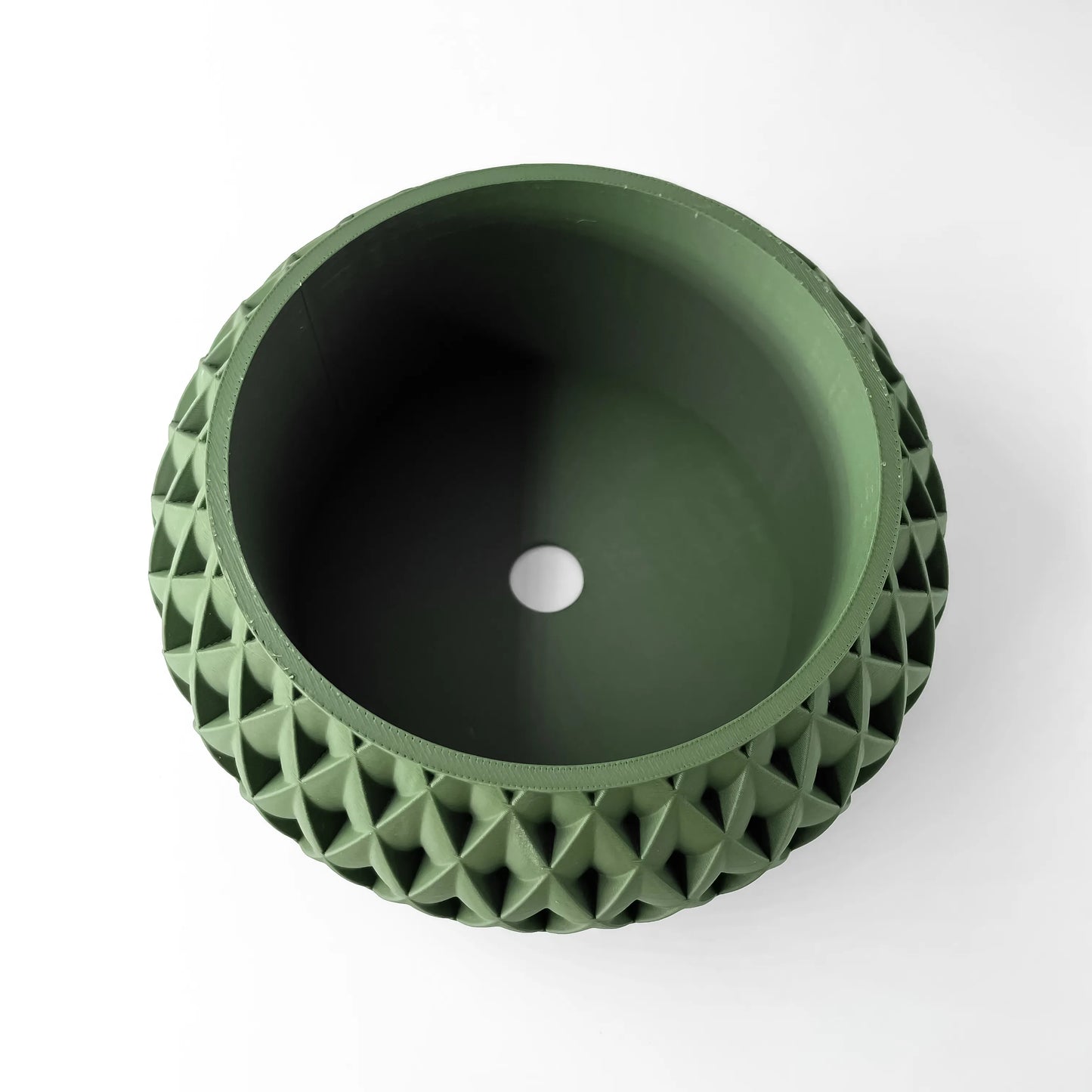 Pot décoratif vert foncé en plastique avec surface extérieure à motif géométrique en relief, forme ronde avec ouverture.