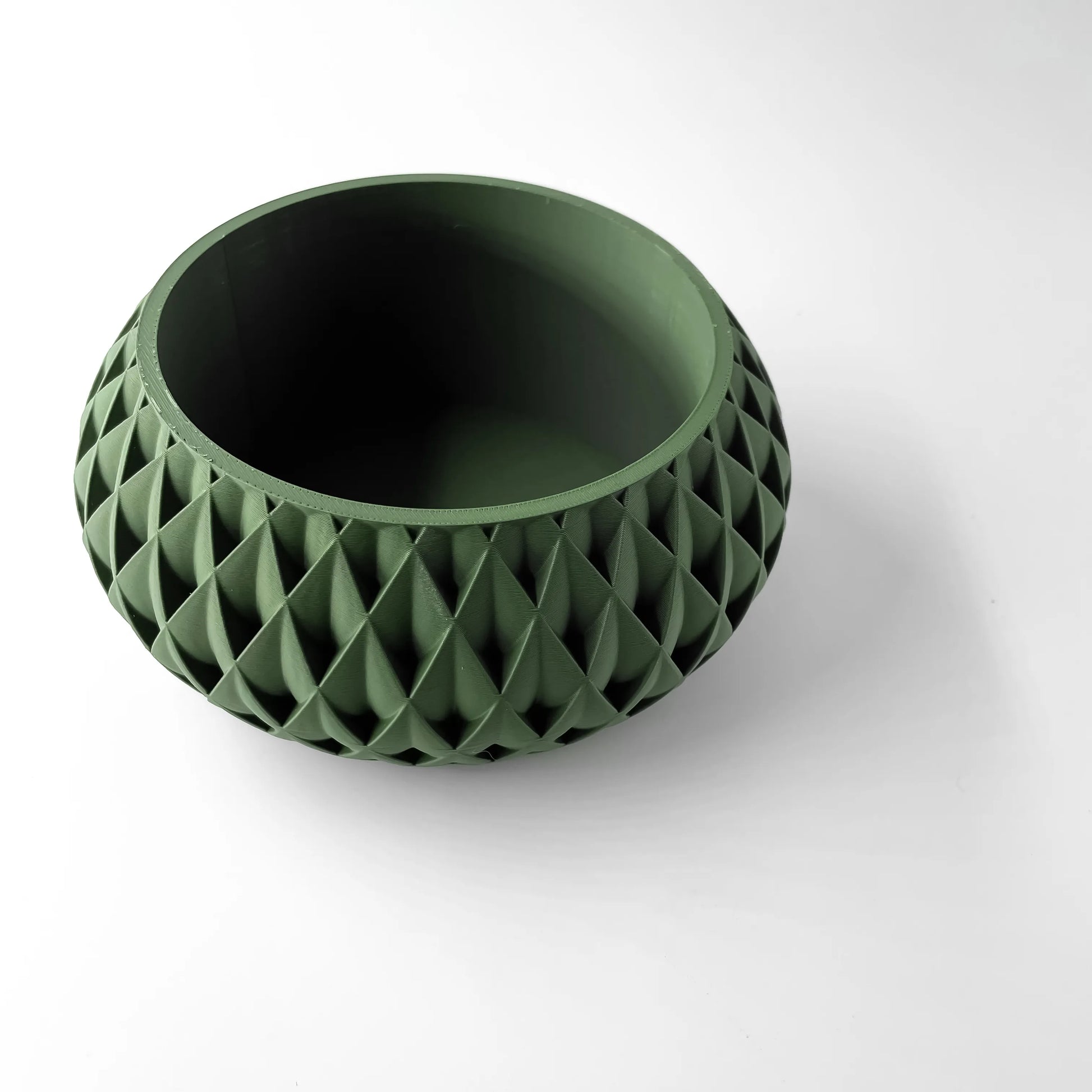Pot décoratif rond vert foncé avec surface géométrique en relief, motif triangulaire entrelacé, design moderne et.