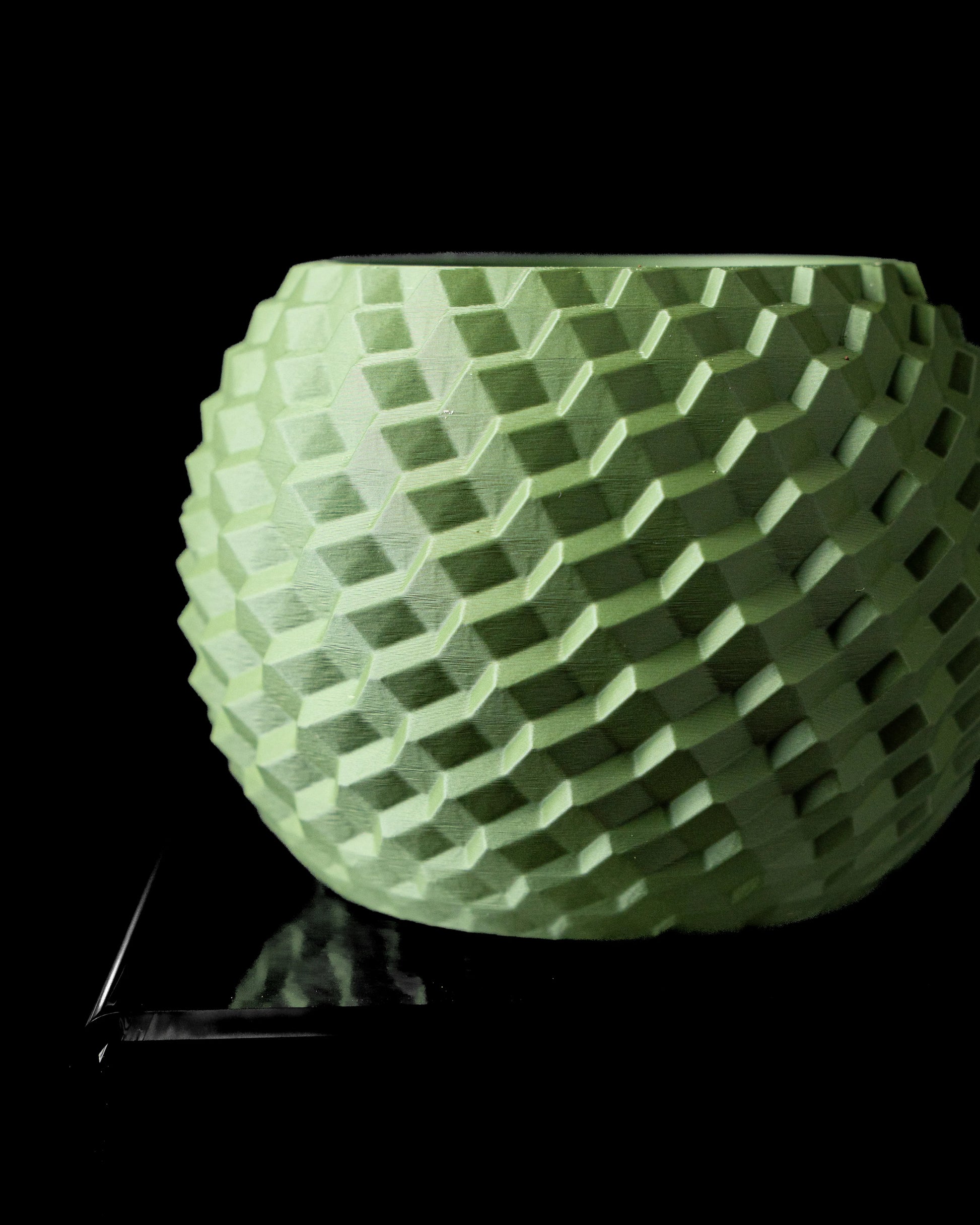 Pot décoratif vert clair mat avec surface texturée hexagonale en relief rappelant des pavés, forme arrondie évasée.