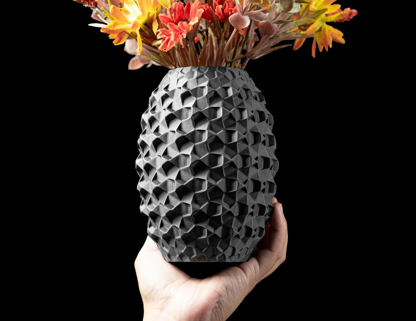 Vase anthracite durable au design contemporain, surface texturée en relief géométrique, forme compacte tenue à la main.