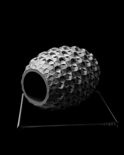 Vase ovale gris foncé avec surface géométrique en relief, posé sur support métallique minimaliste noir.