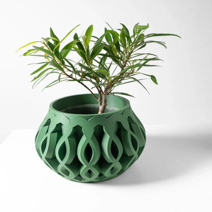 Pot décoratif vert foncé en plastique moderne avec motifs ajourés en forme de maillons, plante verte à l’intérieur.
