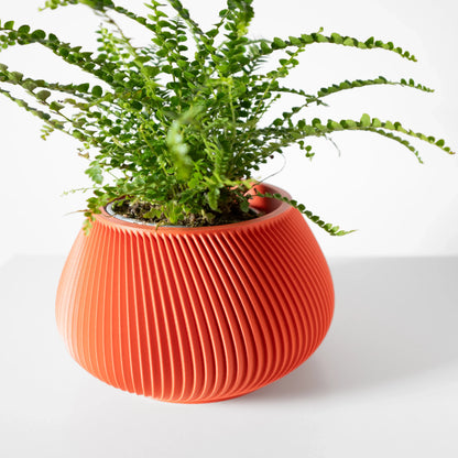 Pot décoratif Davi orange en plastique durable avec surface rainurée au design contemporain, plante verte à l'intérieur.