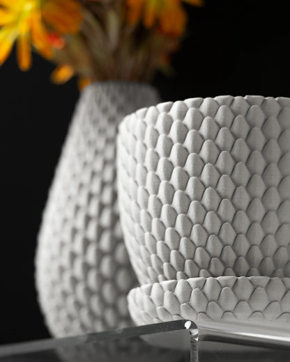 Pot décoratif blanc avec motif écaille de dragon en relief, forme arrondie et bord légèrement évasé, accompagné d'une.