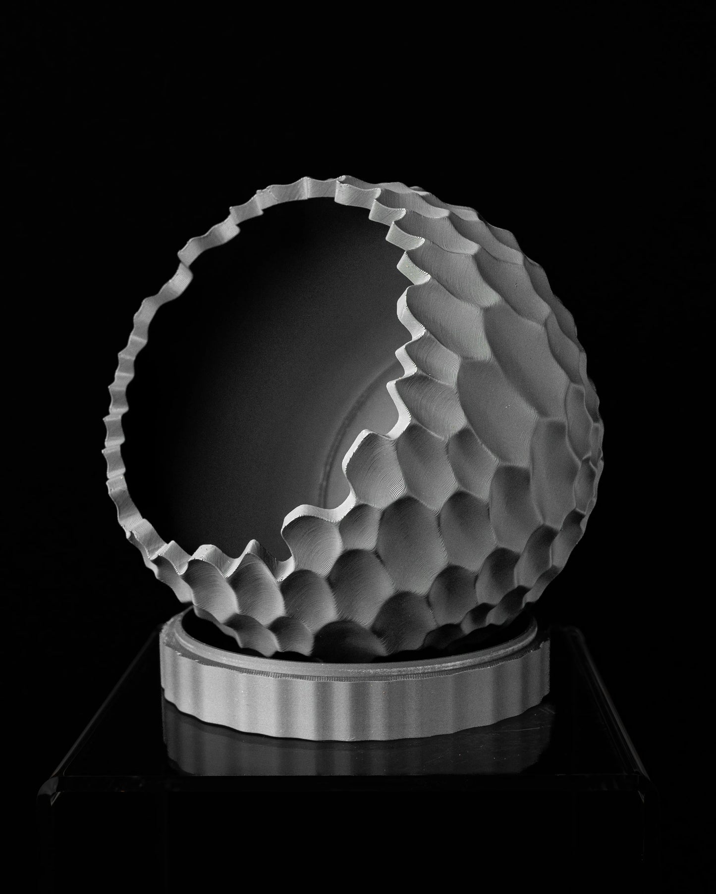 Pot décoratif gris clair en forme sphérique avec surface texturée en relief irrégulier, posé sur un socle cylindrique lisse.