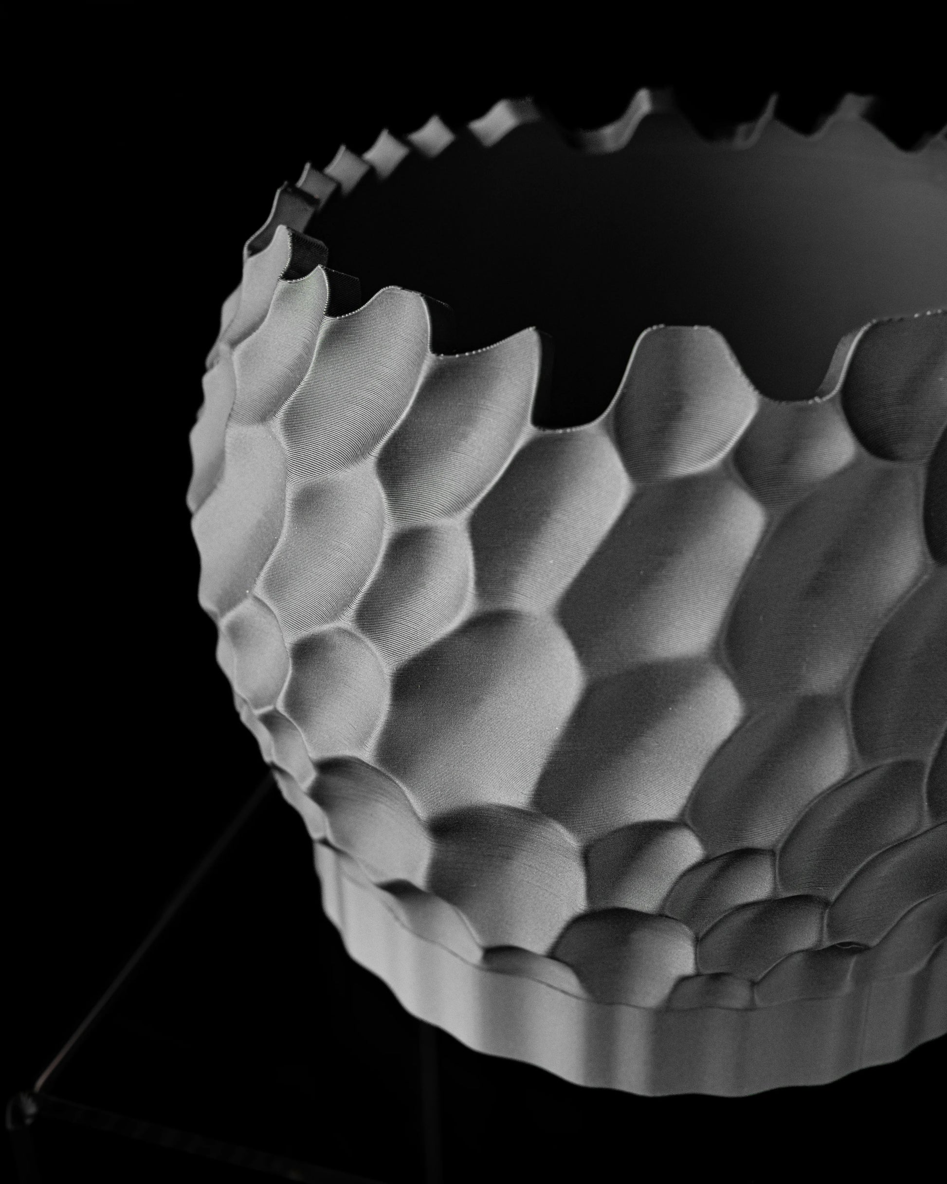 Pot décoratif gris clair avec motif hexagonal en relief et bords irréguliers, aspect moderne et structuré.