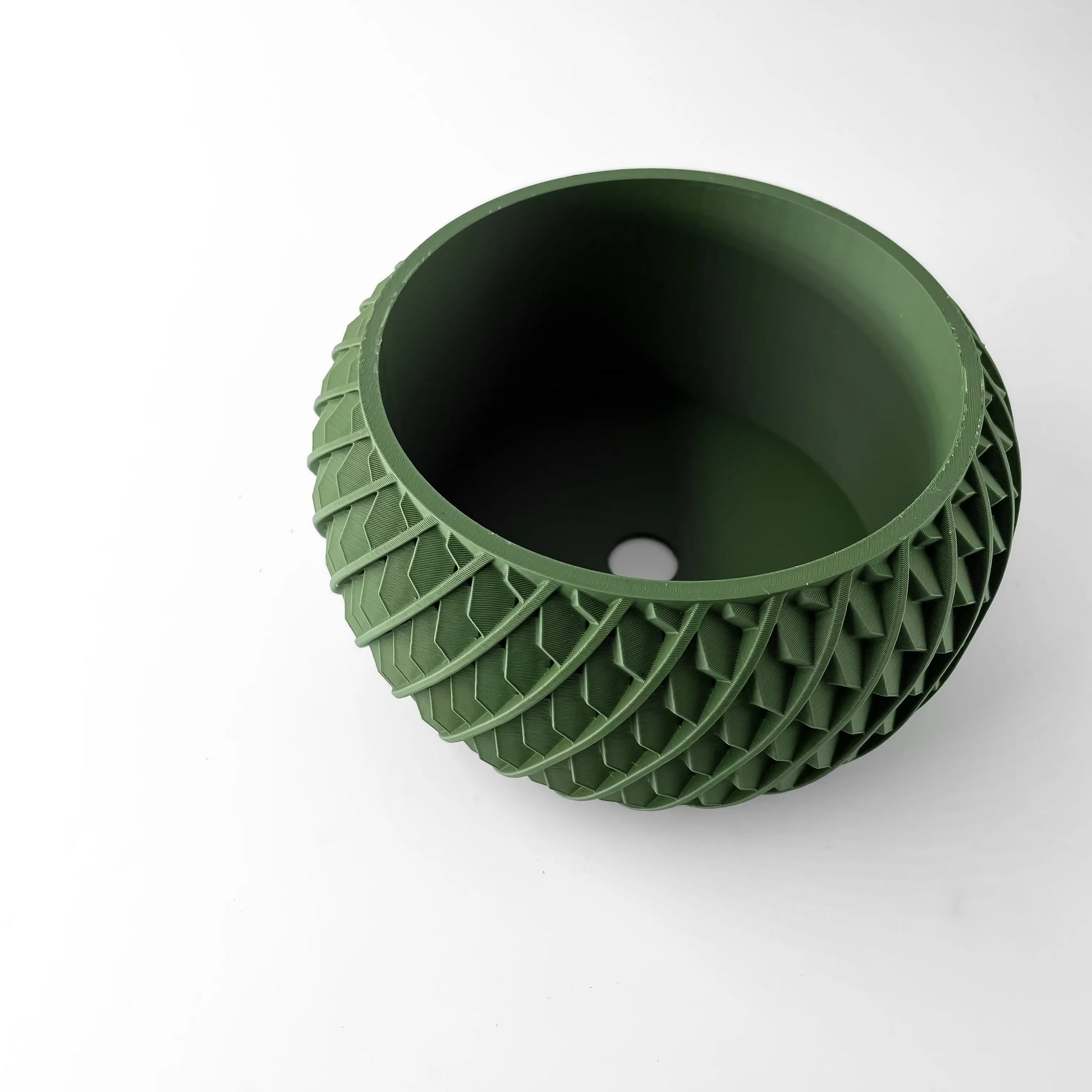 Pot décoratif vert foncé avec motif géométrique texturé en relief sur toute sa surface extérieure, forme ronde et creuse.