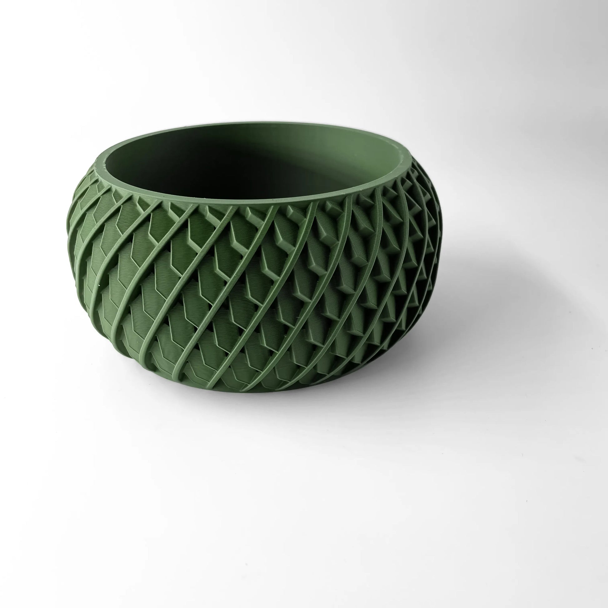 Pot décoratif vert foncé en matériau texturé, forme ronde avec motif géométrique en relief sur toute la surface.