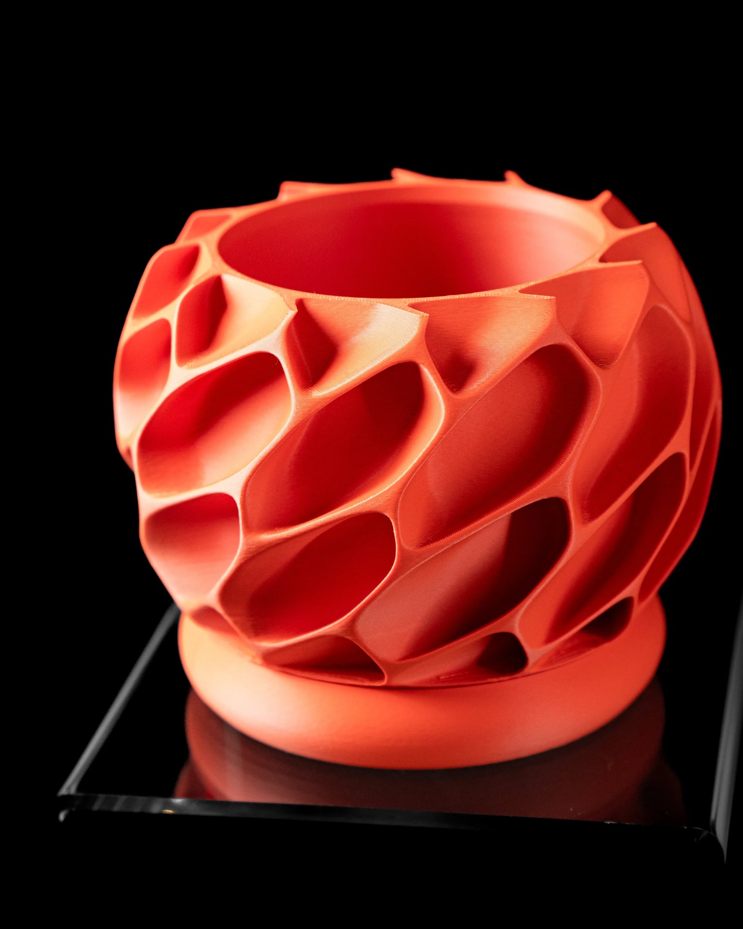 Pot décoratif orange vif avec structure creuse organique en relief, forme ronde et base plate.