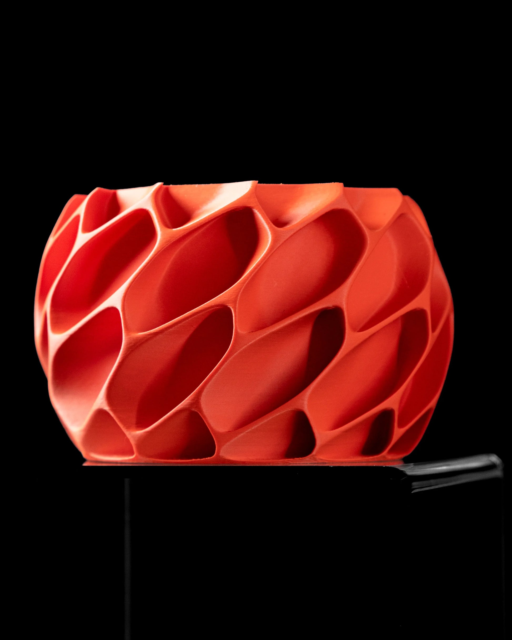 Pot décoratif rouge vif en résine avec surface texturée ondulée et design moderne, forme arrondie.