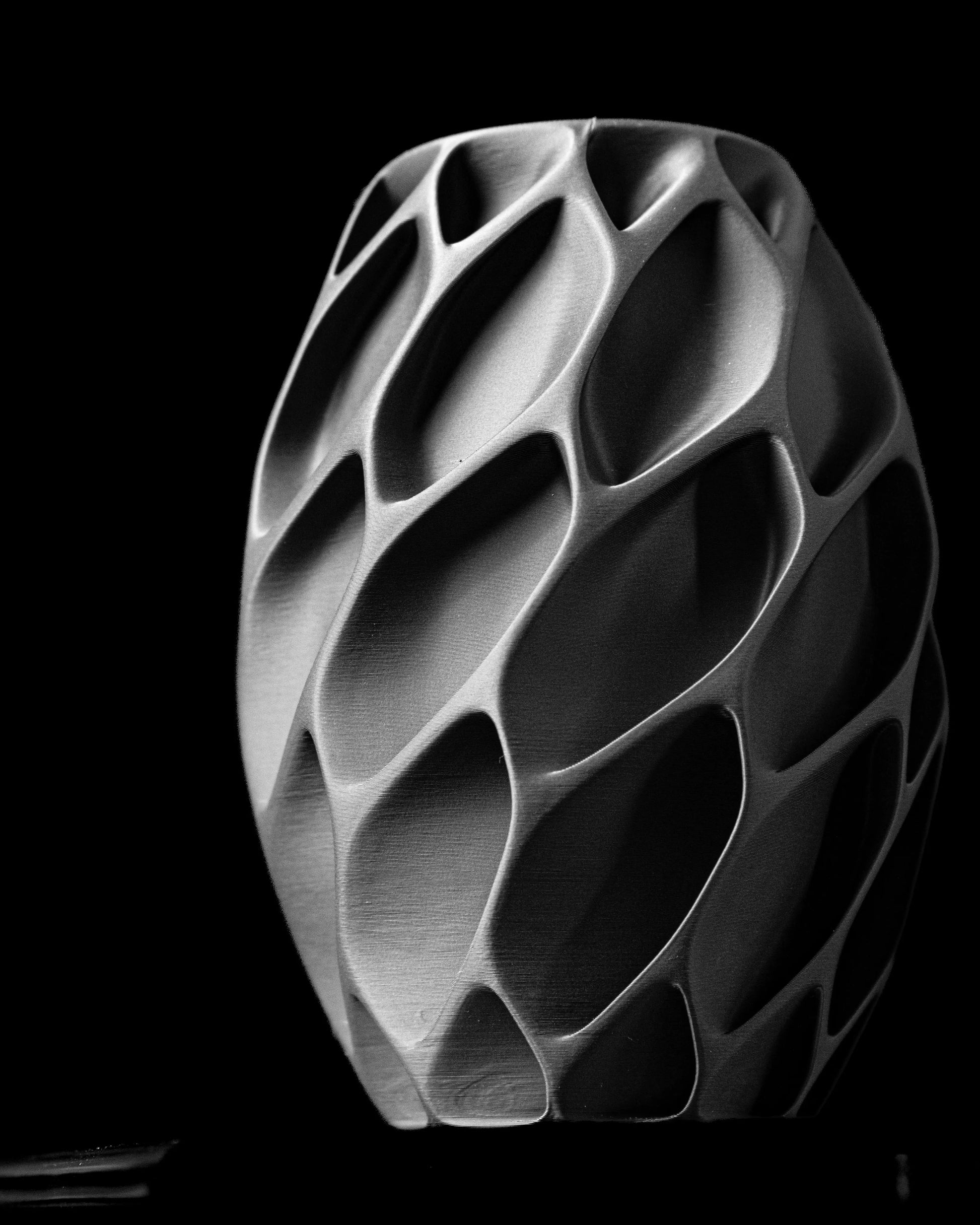 Vase gris foncé avec surface texturée en motifs géométriques creusés, forme ovale élancée et finition mate, style moderne et