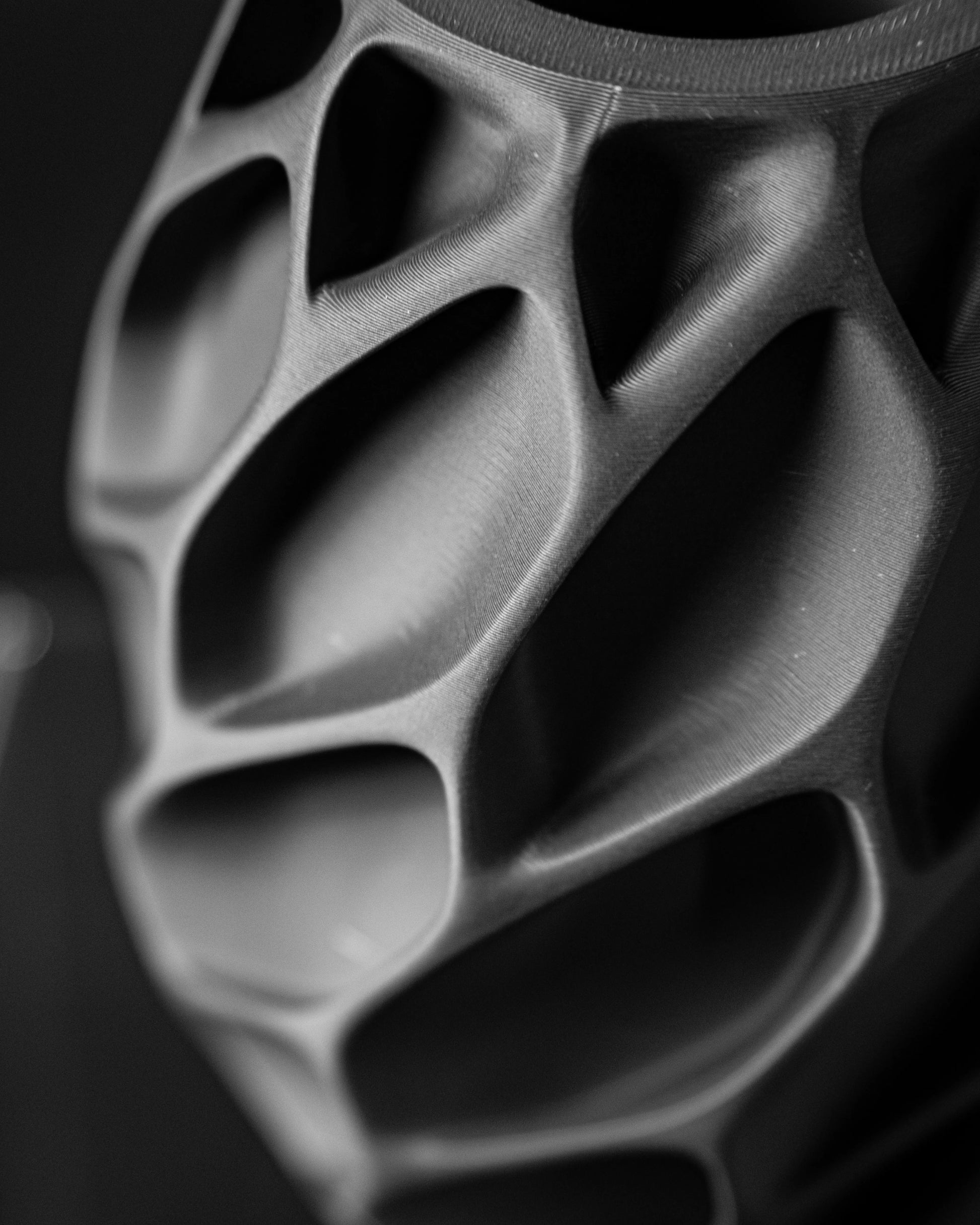 Vase noir mat à surface sculptée en relief avec motifs creux géométriques et finition lisse.