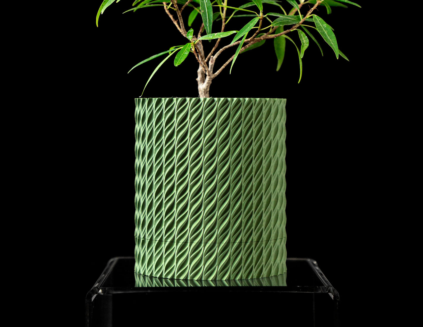 Pot décoratif durable vert forêt à design contemporain avec texture tressée, posé sur un support transparent.