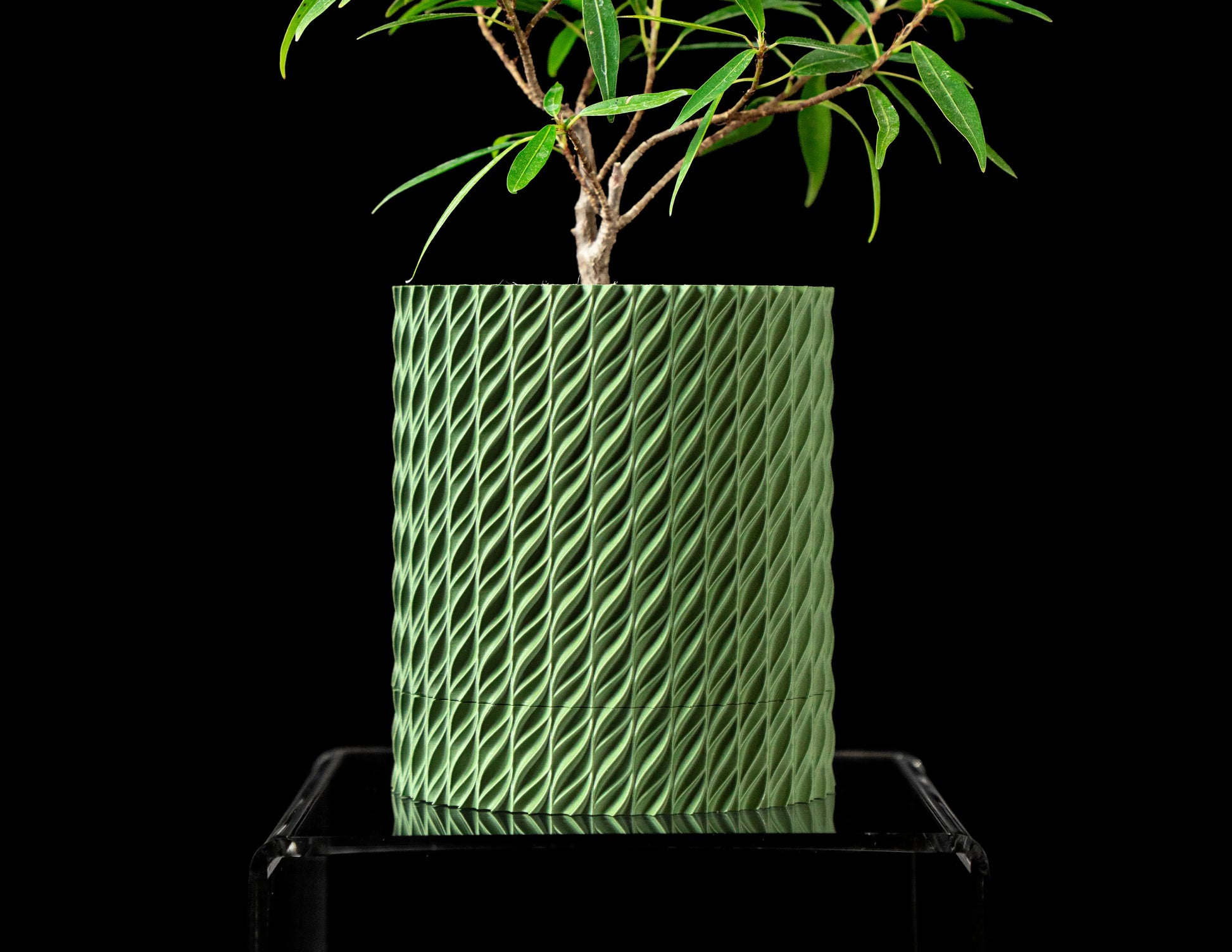 Pot décoratif durable vert forêt à design contemporain avec texture tressée, posé sur un support transparent.