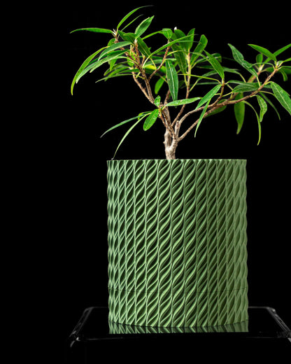 Pot décoratif vert à surface texturée en motifs torsadés, forme cylindrique moderne, plante en pot avec feuillage fin.