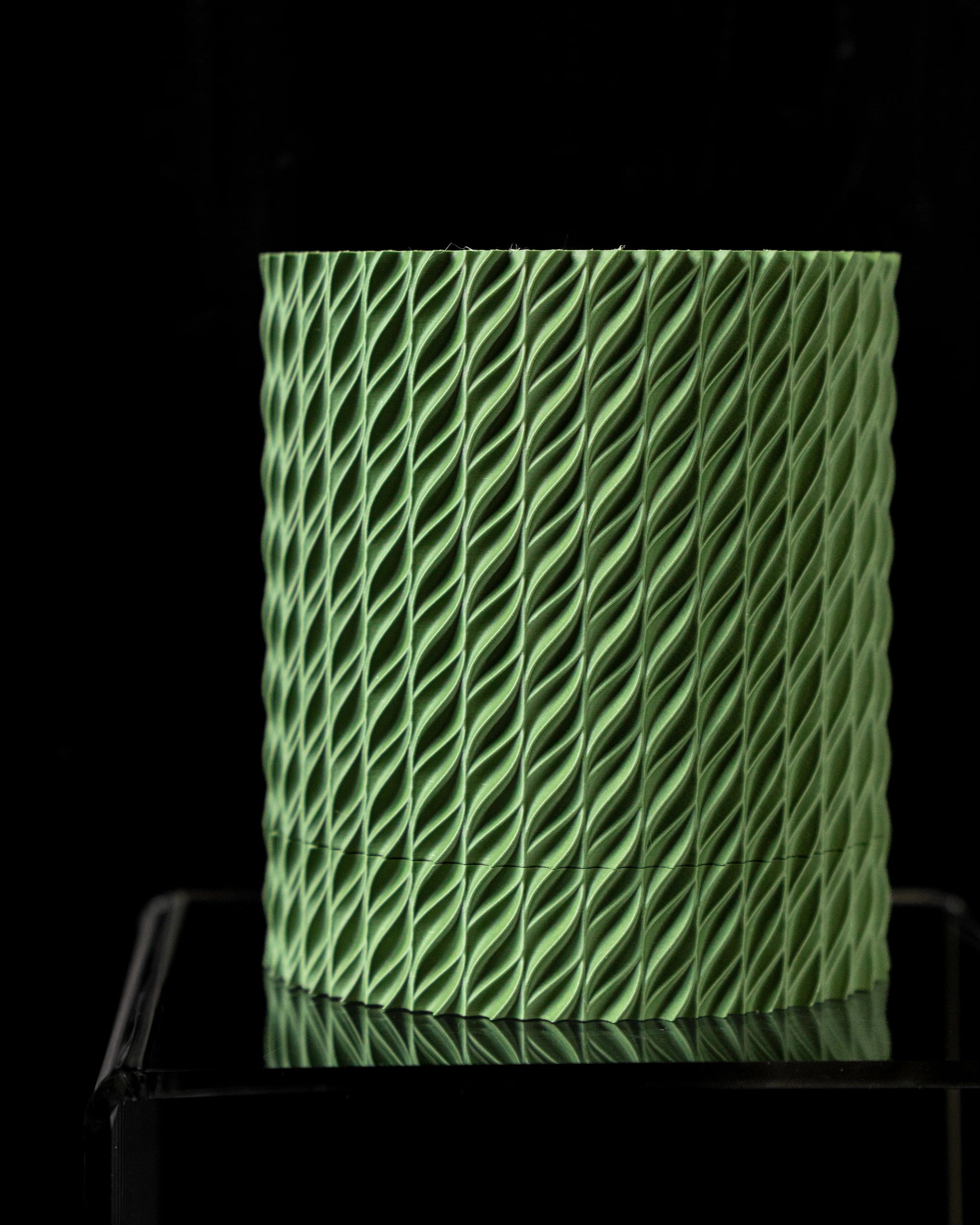 Pot décoratif vert clair cylindrique avec surface texturée en motif torsadé, effet 3D moderne.