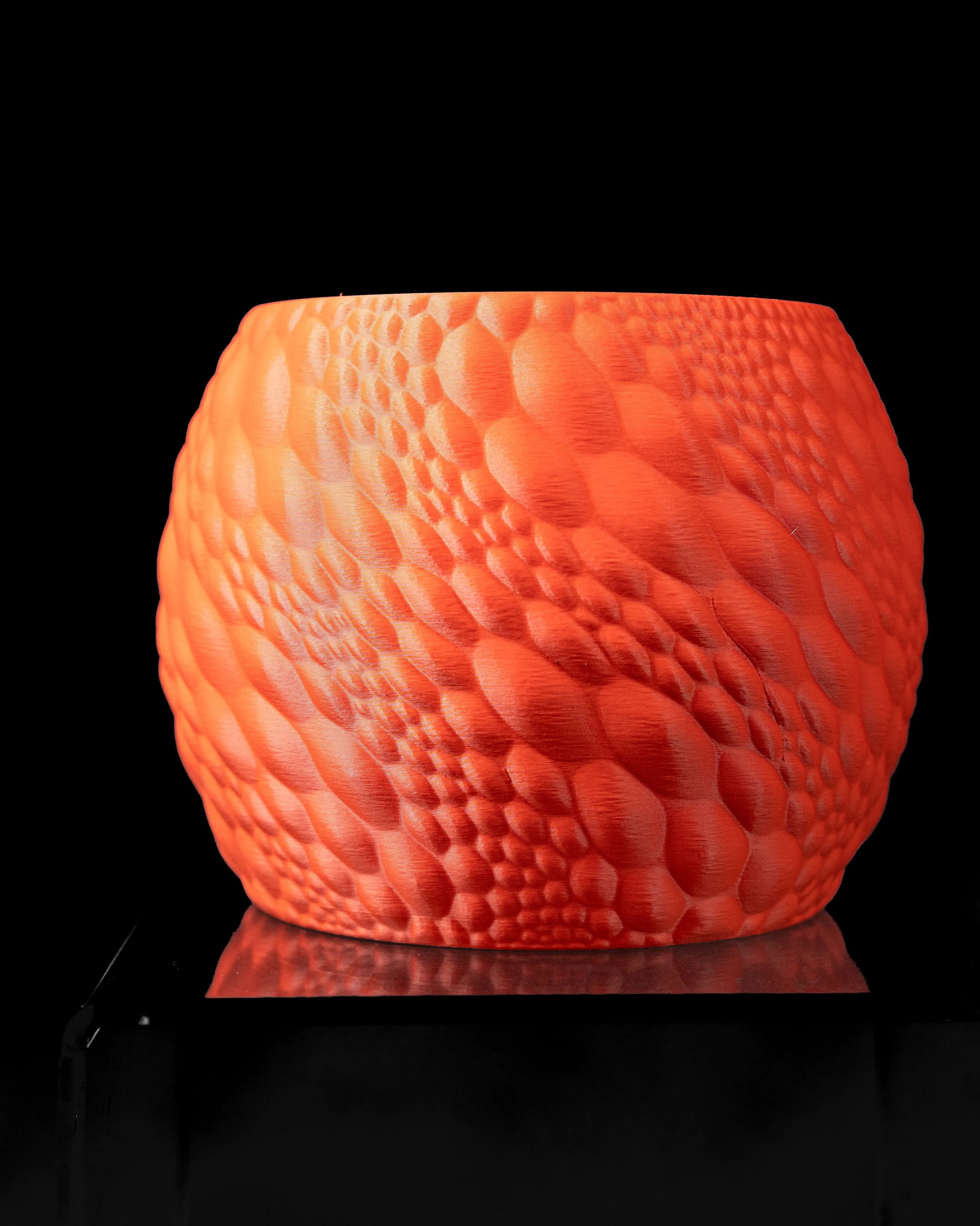 Pot décoratif orange avec texture organique en relief rappelant des motifs naturels, forme arrondie et ouverture large.