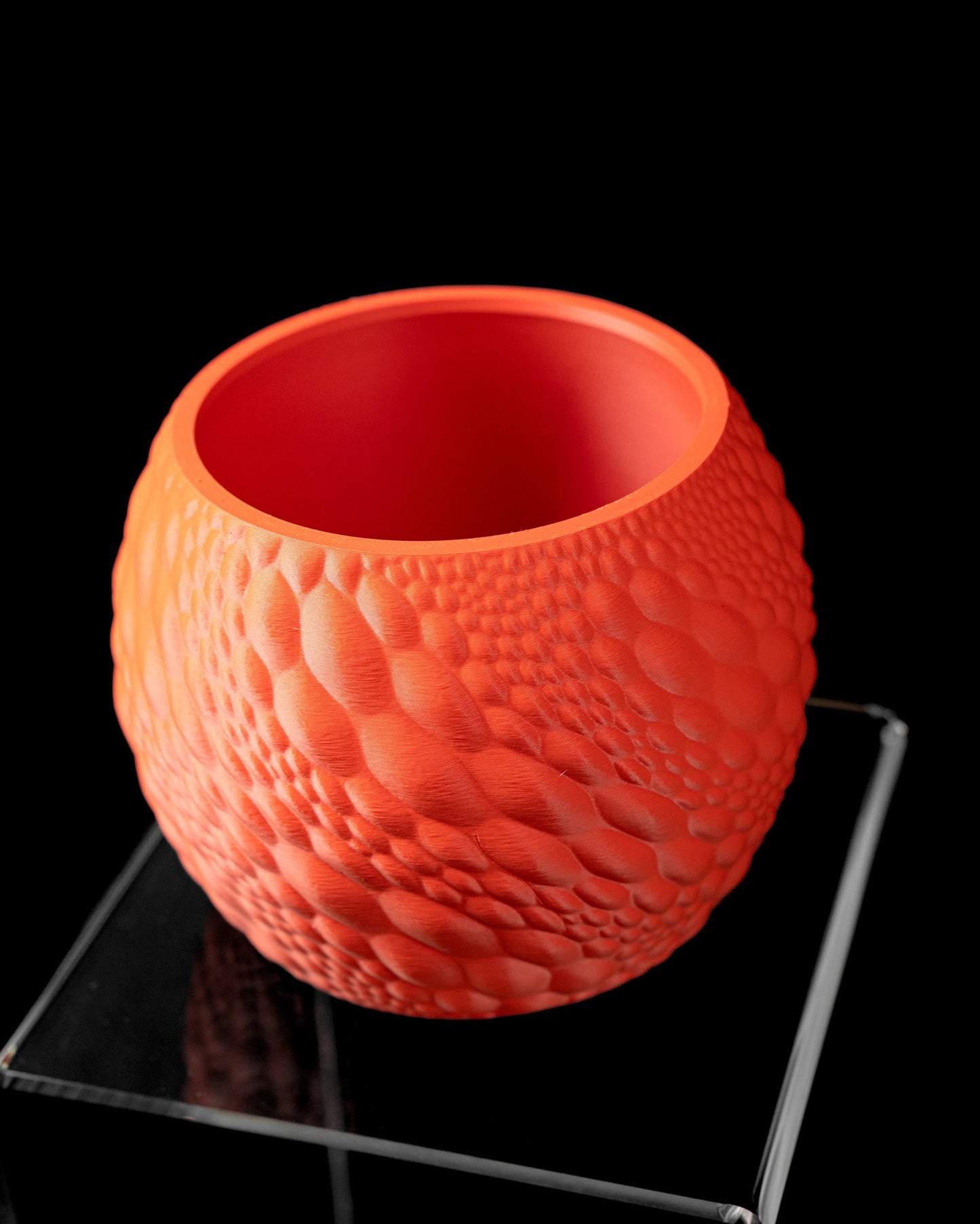 Pot décoratif rond orange texturé avec motifs en relief rappelant des écailles, finition mate, ouvert sur le dessus.