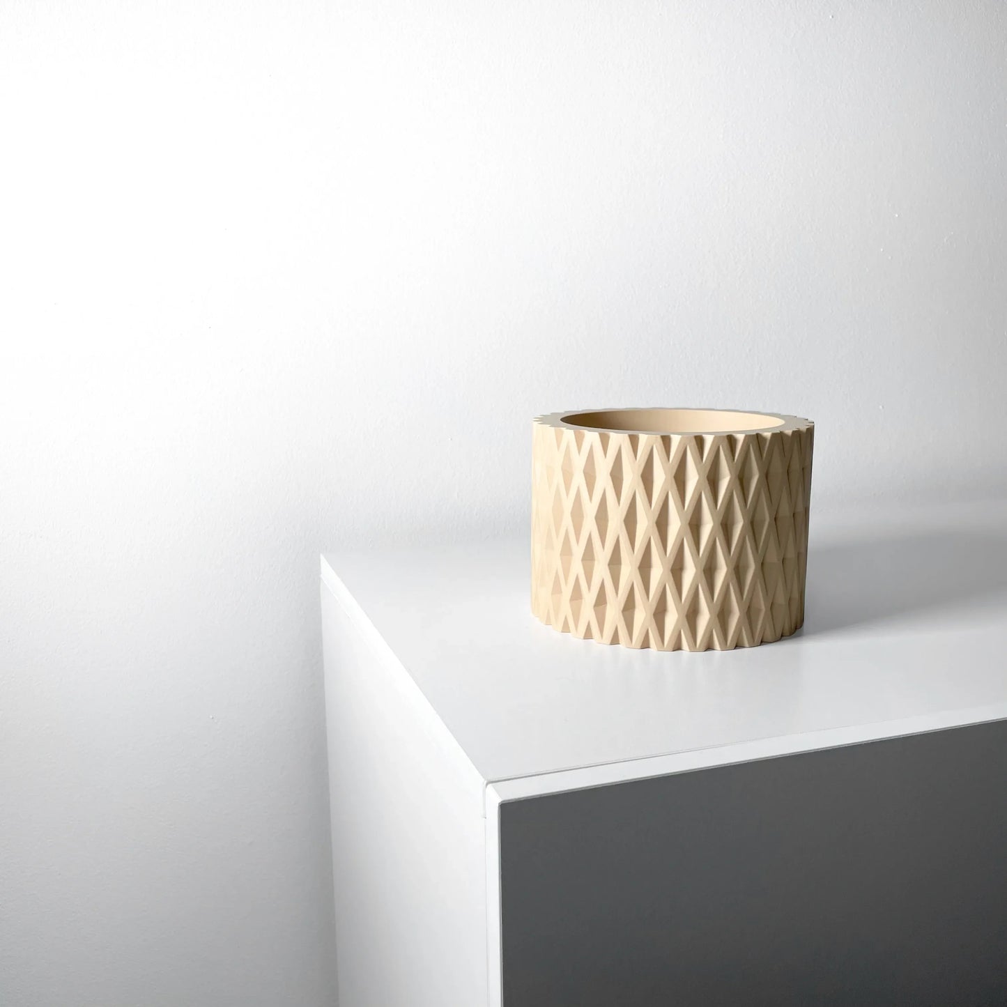 Pot décoratif beige avec surface texturée en relief en forme de losanges, forme cylindrique et finition mate.