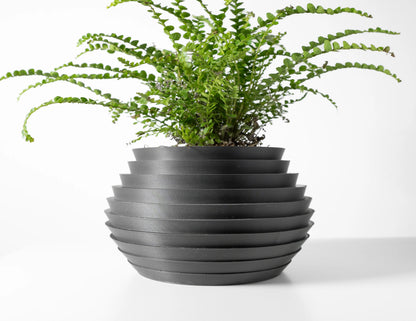 Pot décoratif anthracite en matériau durable à design contemporain avec surface striée et forme ronde aplatie, contenant une .