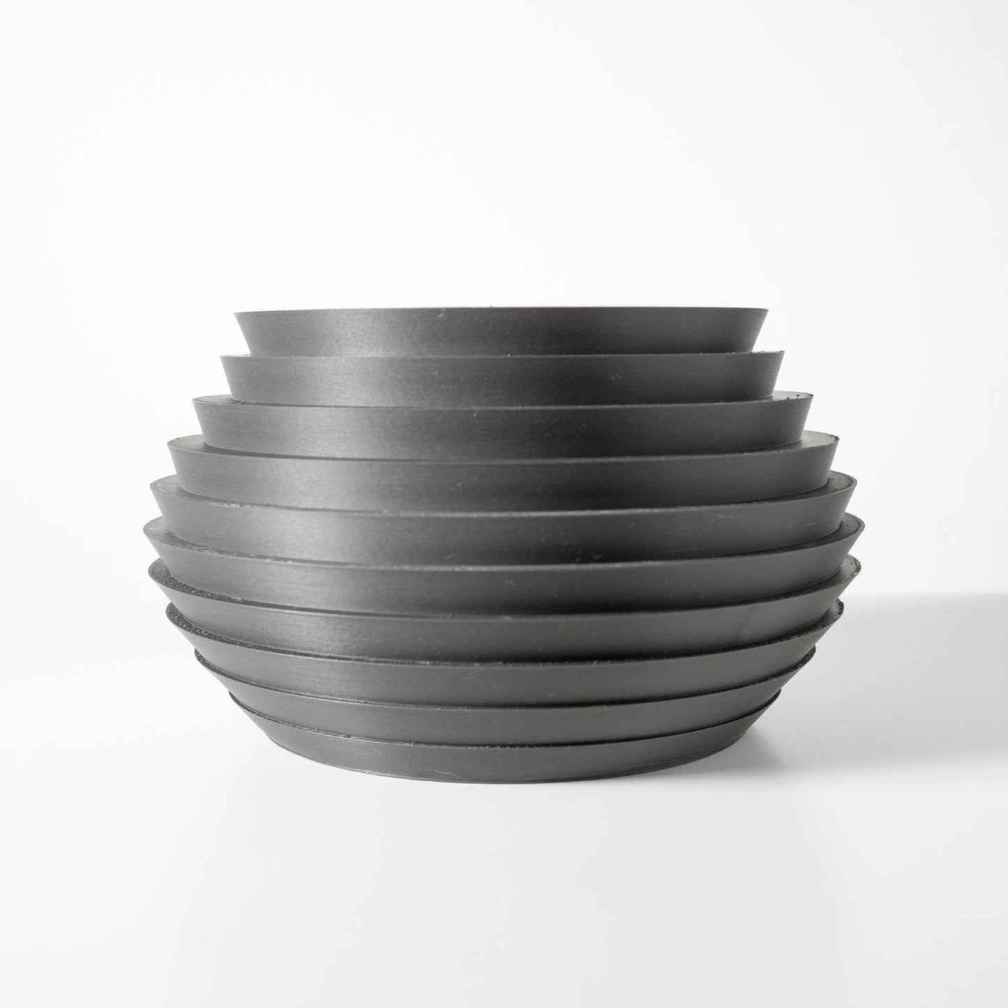 Pot décoratif moderne en métal gris foncé avec surface nervurée en cercles horizontaux superposés, forme arrondie et large.