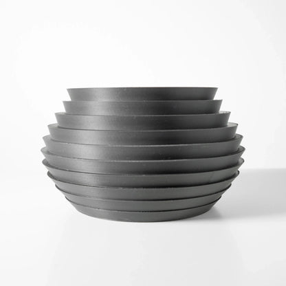 Pot décoratif moderne en métal gris foncé avec surface nervurée en cercles horizontaux superposés, forme arrondie et large.