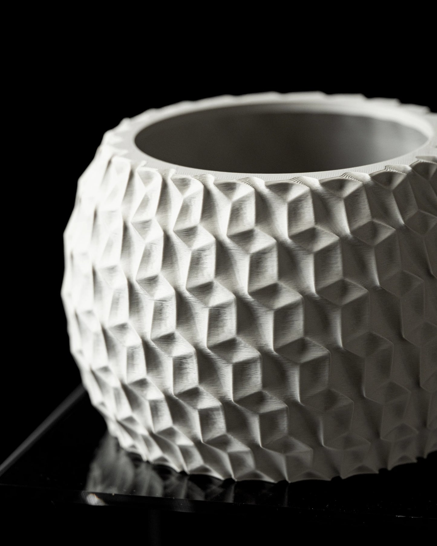 Pot décoratif blanc mat en forme cylindrique avec motif géométrique hexagonal en relief, surface texturée et moderne.