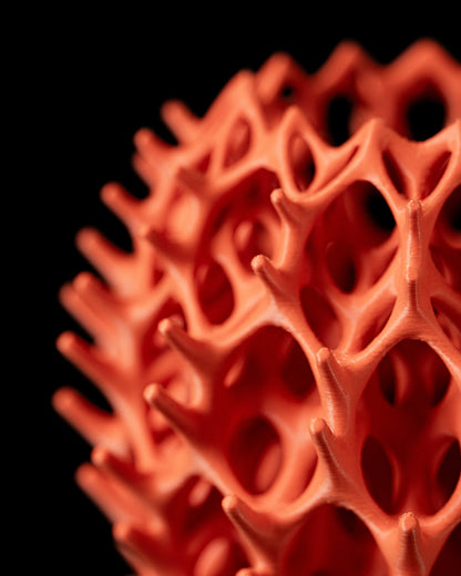 Vase orange mat design organique avec alvéoles irrégulières et surface texturée, style moderne sculptural.