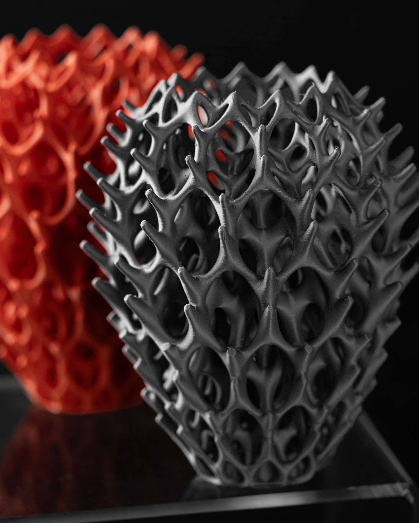 Vase moderne noir mat à structure ajourée complexe rappelant un réseau organique, forme arrondie légèrement effilée vers le.