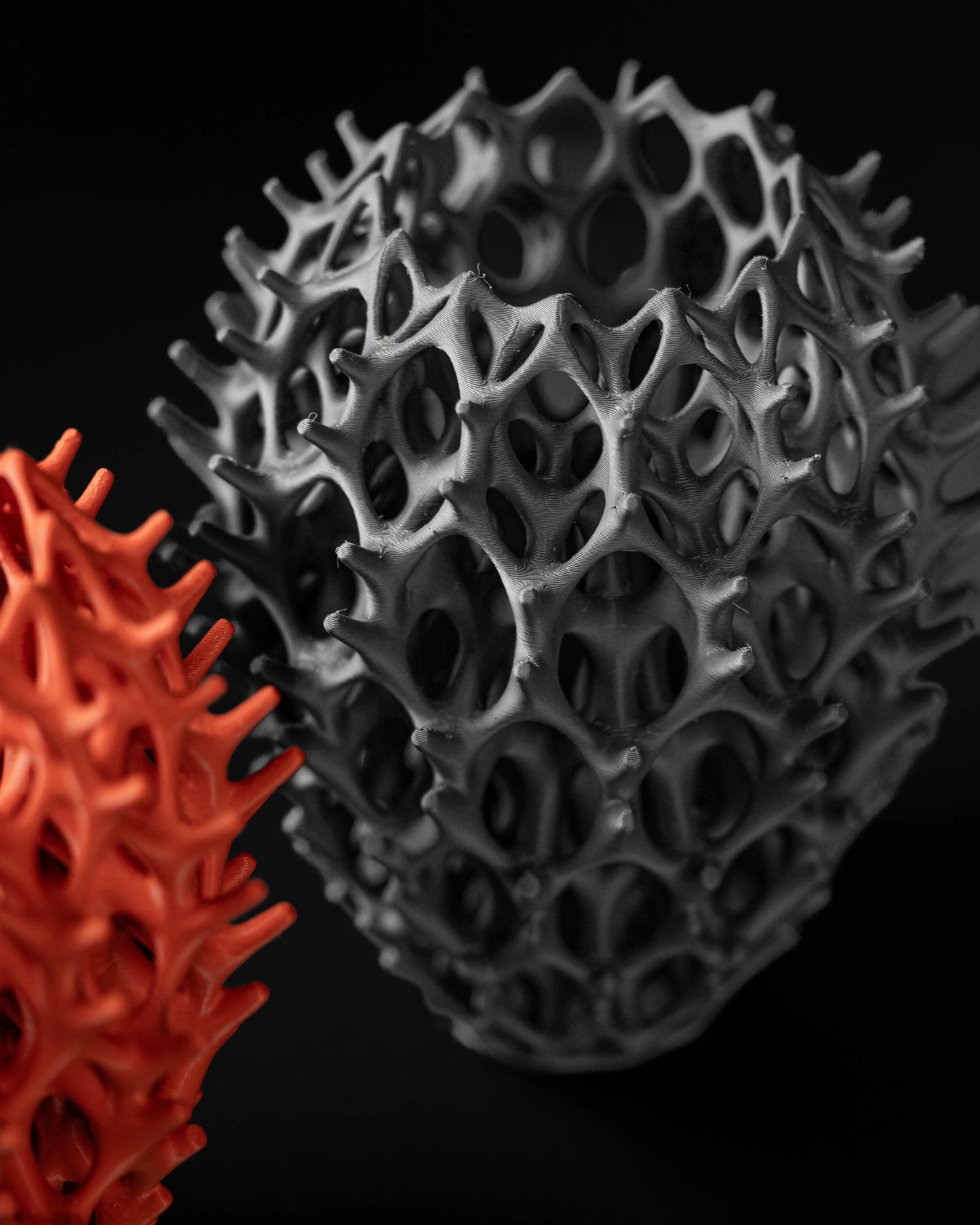 Vase sculptural noir mat en forme organique perforée avec motifs alvéolés, style moderne machine.