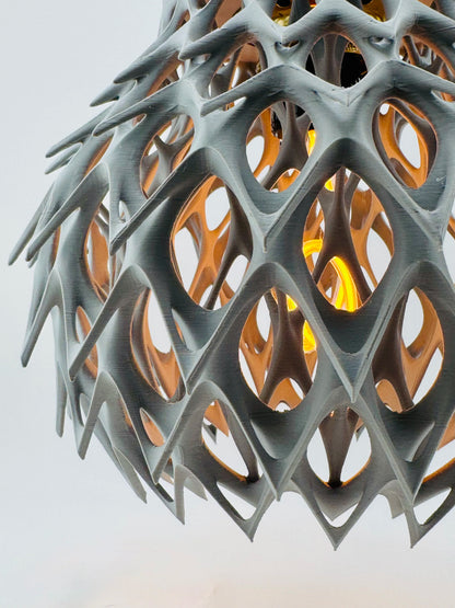 Suspension gris anthracite en plastique ajouré, design contemporain et durable, lumière chaude diffuse.