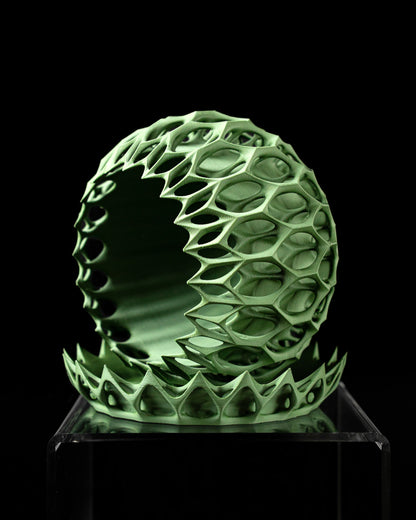 Pot décoratif vert clair en forme sphérique avec motif alvéolé tridimensionnel ajouré, posé sur un socle assorti.