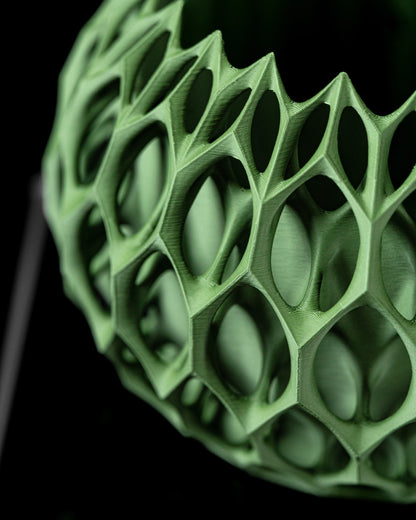 Pot décoratif vert clair en matériau moderne avec surface ajourée de formes géométriques hexagonales irrégulières.