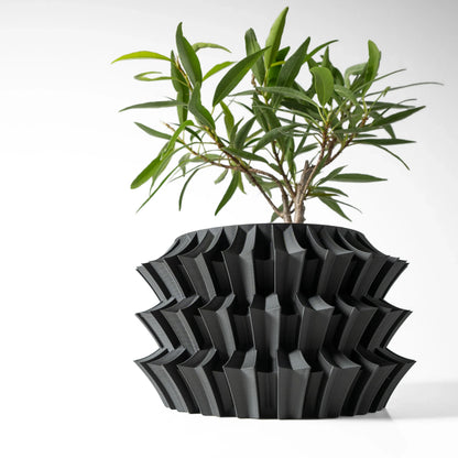 Pot décoratif noir mat en plastique moderne avec design géométrique en relief, plante verte aux feuilles étroites suspendue.