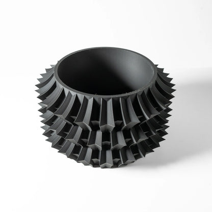 Pot décoratif noir mat avec structure géométrique épaisse en relief, forme cylindrique à bords arrondis.