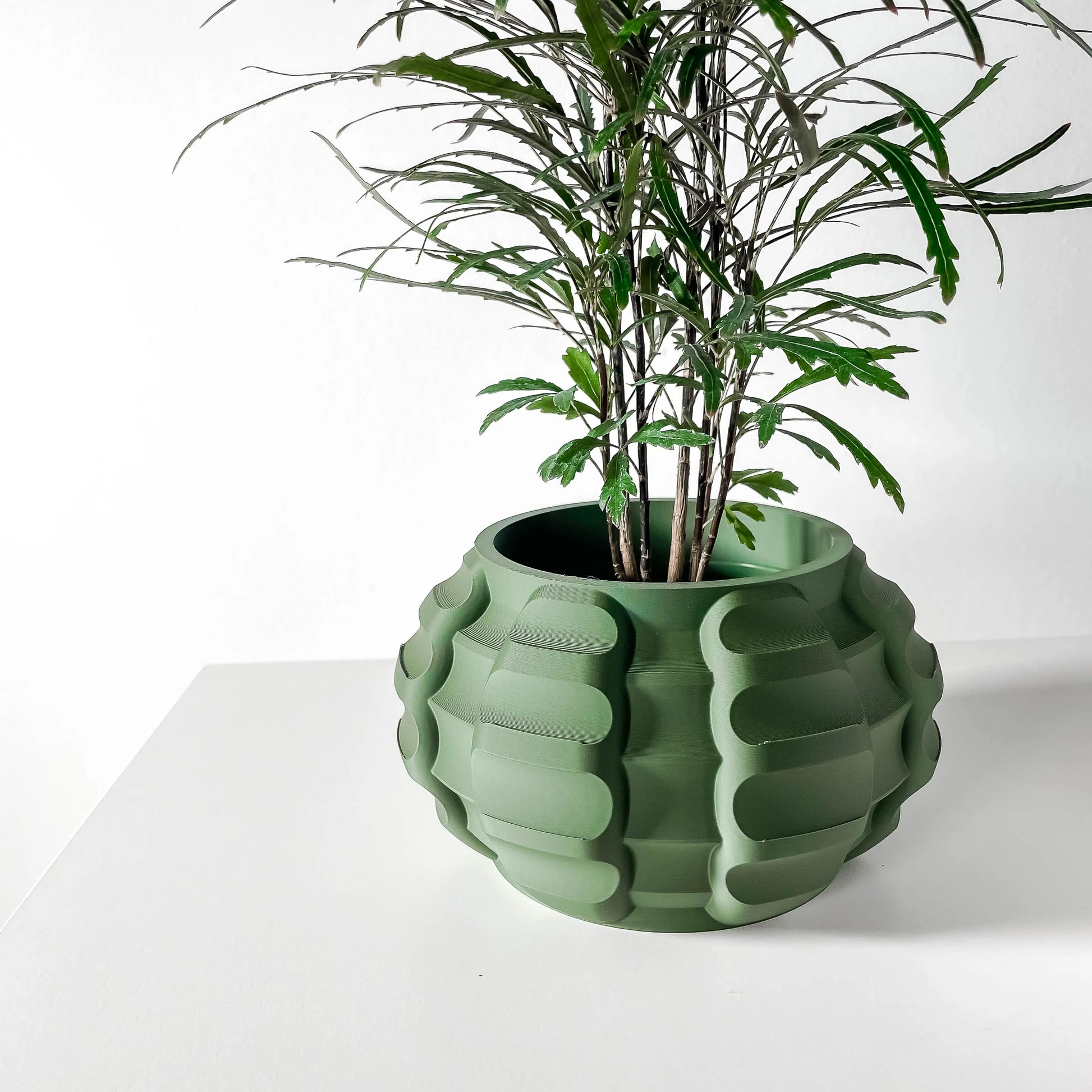 Pot décoratif en jute vert forêt avec surface texturée en relief, design contemporain et durable, plante verte à l’intérieur.
